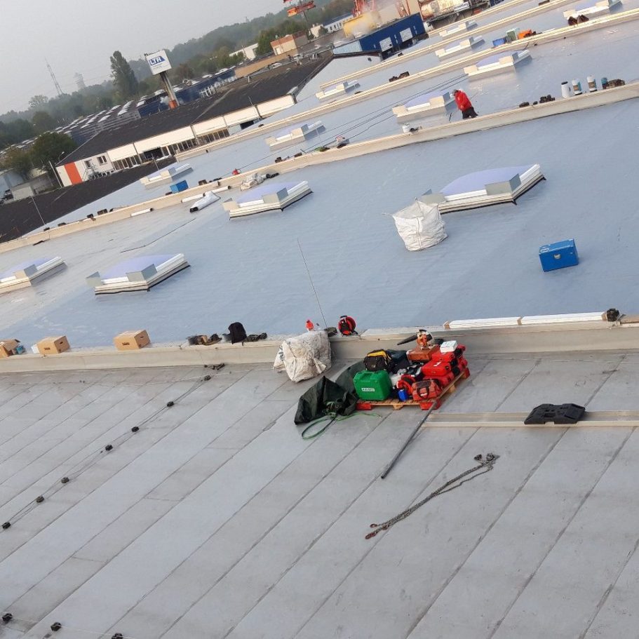 Flachdach Sanierung Dachansicht mit Dämmmaterial, Werkzeug und Containern auf einer Industriehalle.