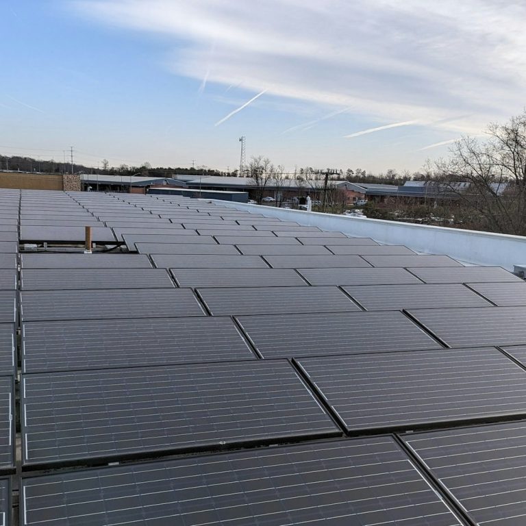 Dach auf einer Industriehalle mit Solarpanelen, die in einem klaren Himmel installiert sind.