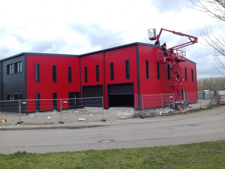 Industriehalle Fassade Neue Fassade in rot und schwarz einer Industriehalle mit Baugerüst und Arbeiter bei der Montage